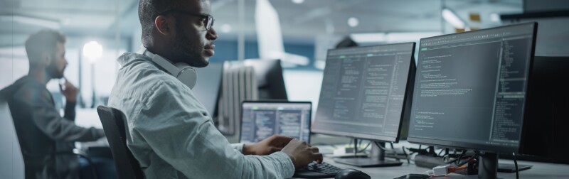 Male IT Programmer monitors security metrics at workstation computer.