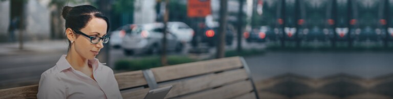 a person reads a tablet while sitting on a park bench in New York City