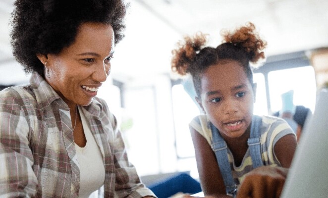 Woman working at a laptop while her daughter looks at the screen