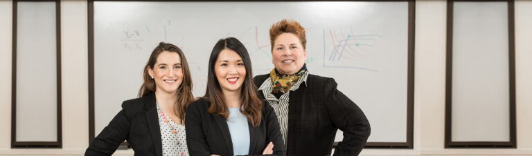 three women in black blazers standing together smiling