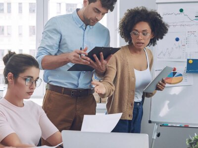 Group of confident young people in smart casual wear discussing business while having meeting in office.