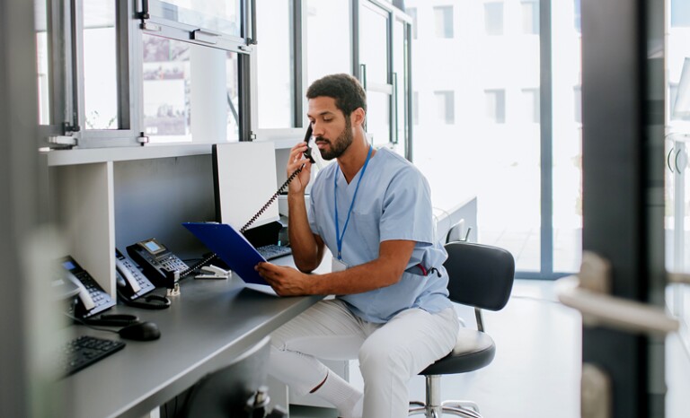 Male healthcare worker speaking on phone and reading chart