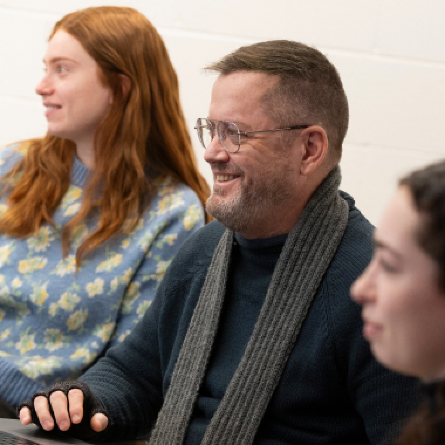 A male student with glasses and a scarf listens during a class discussion.