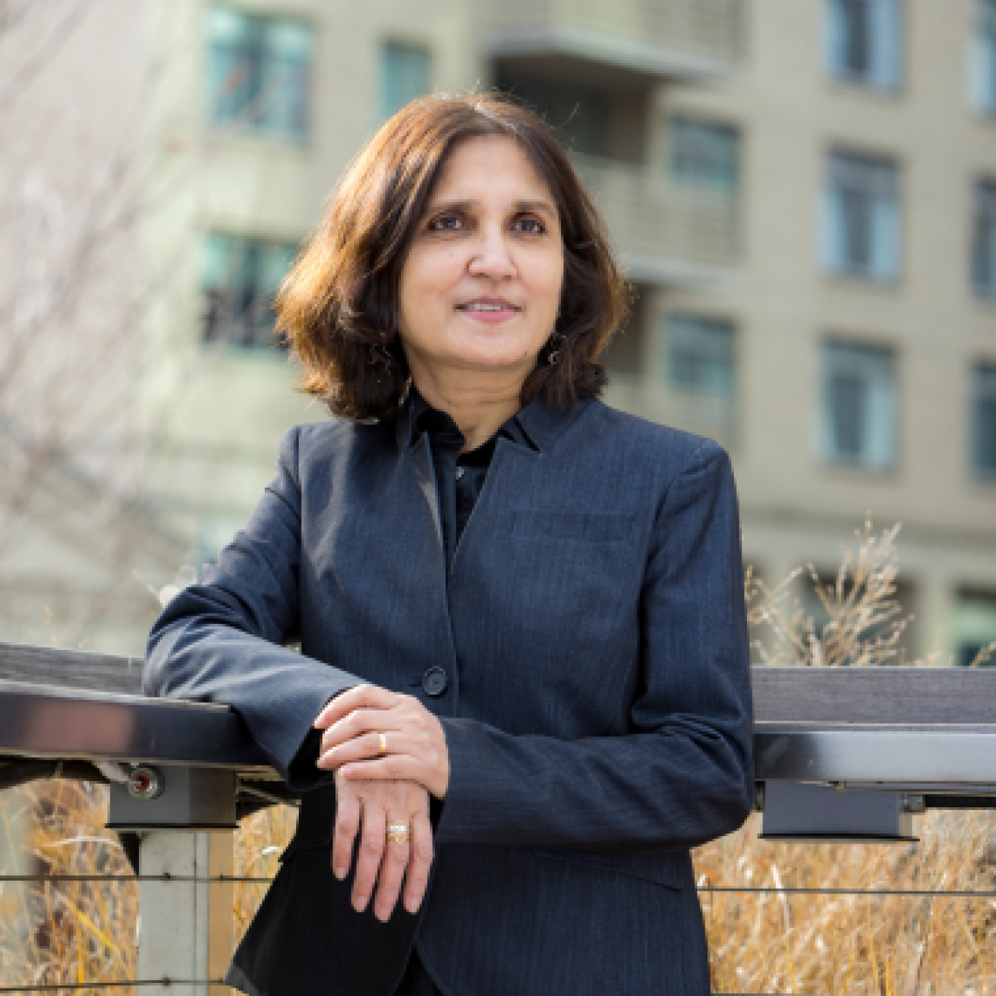 A close-up of a female entrepreneurial professional with arms crossed while leaning against a railing.