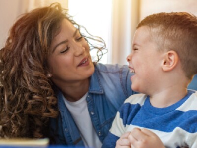 Caregiver and child laughing together in kitchen