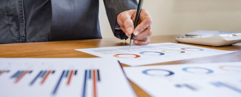 Portfolio manager analyzing financial charts and graphs on paper