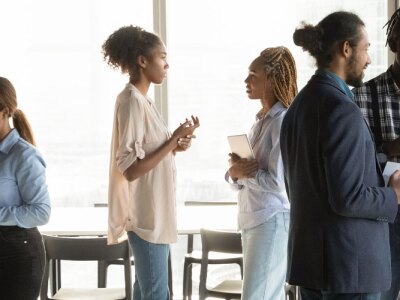 Group of young business professionals network with one another in a corner meeting room.