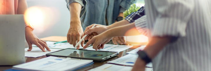people standing around tablet discussing a product