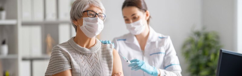 Doctor giving a senior woman a vaccination.