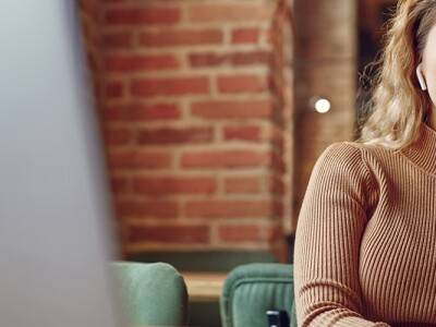 Woman using earphones and laptop for studying at cafe