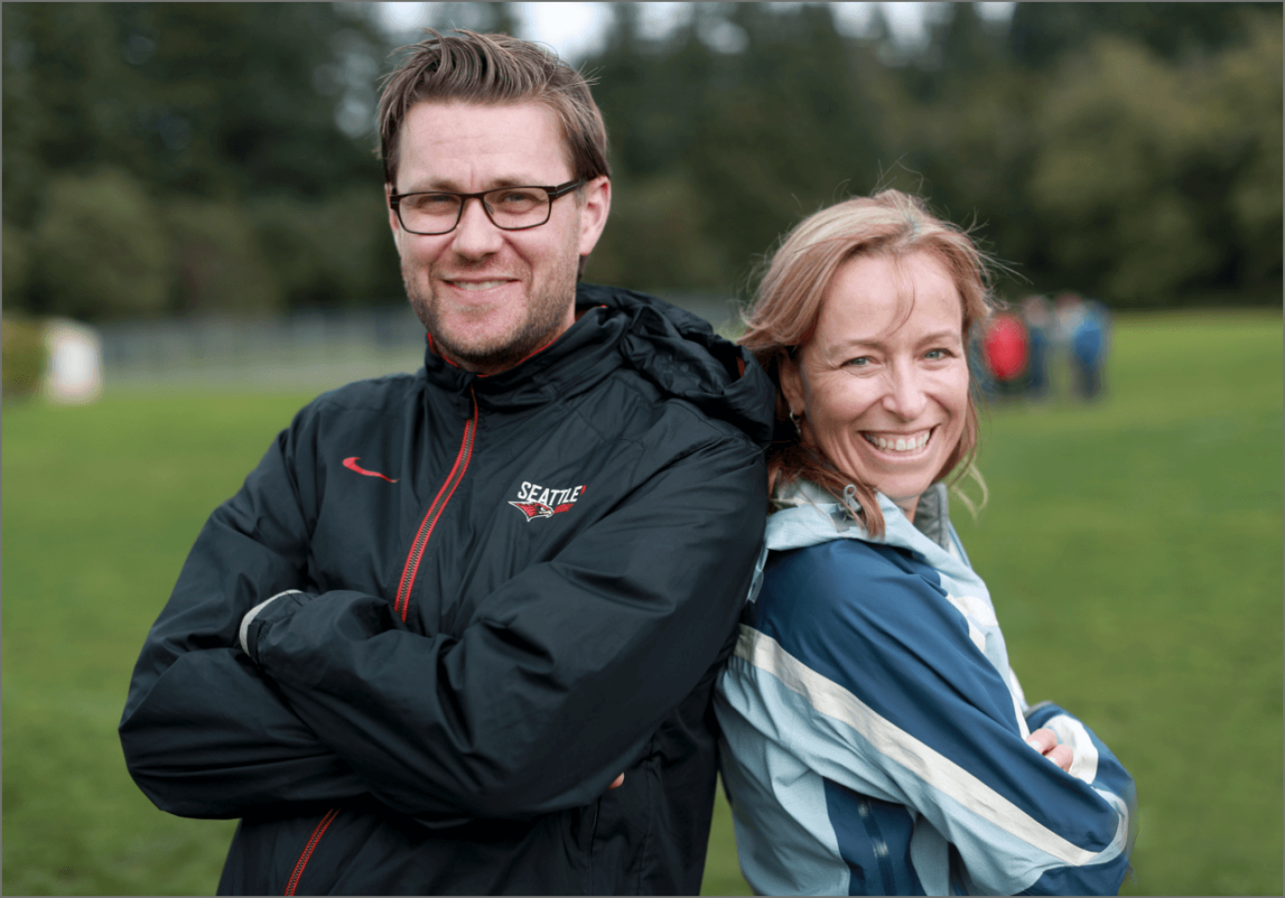 Two MBA students on retreat standing back to back smiling