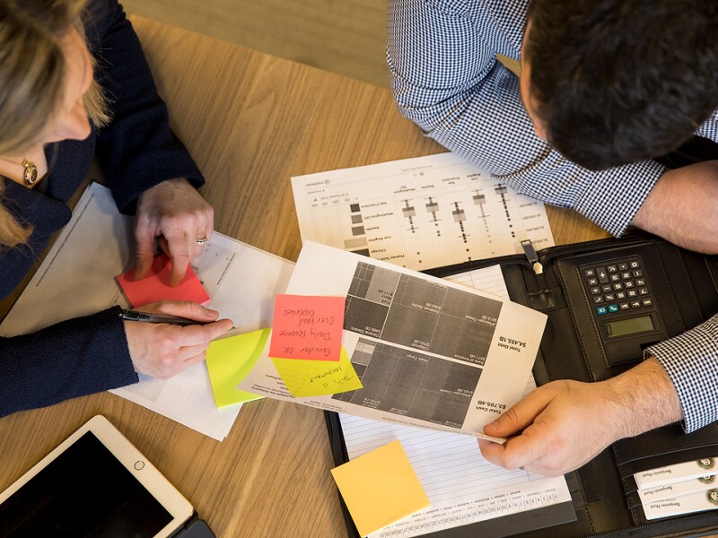 Overhead shot of a man working with paper, sticky notes, and a calculator