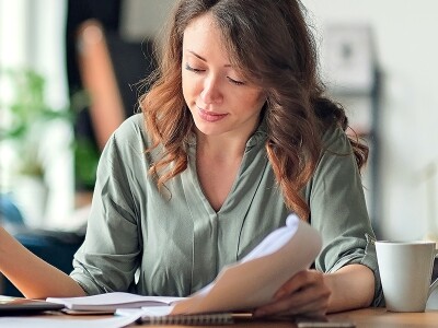 Woman in home office looking at papers and laptop