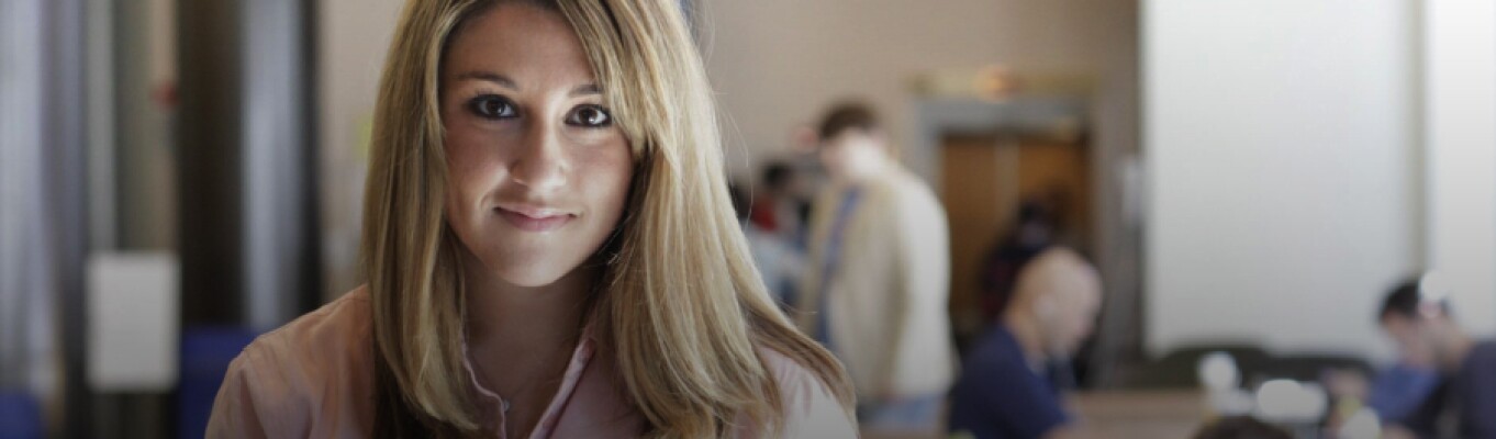 woman in pink shirt smiling while standing in law library
