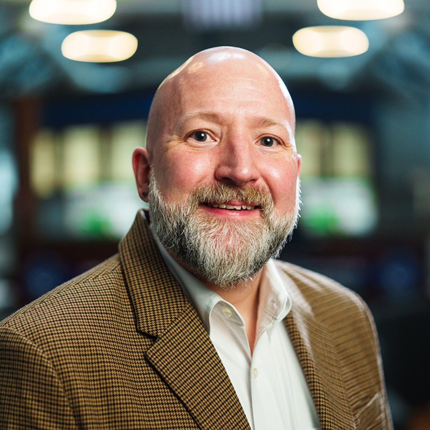 Headshot of Jeremiah Nelson, wearing a brown blazer and white shirt, against a softly blurred indoor background.