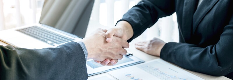 Two people shaking hands across a table