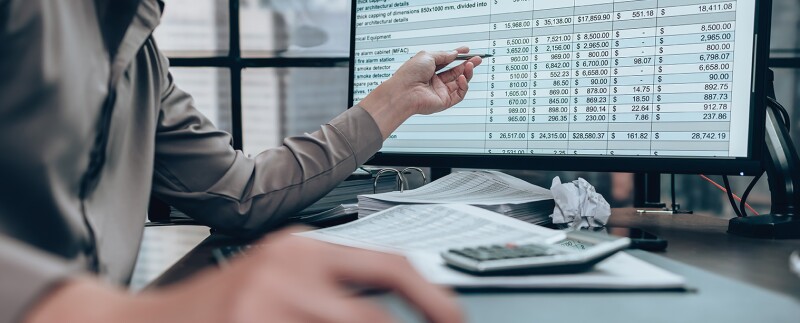 Businessman working on desk and checking cost, balance, and profit reports
