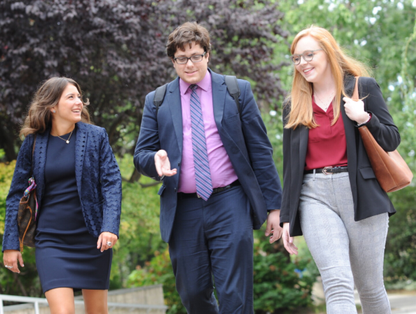 A professionally dressed male Hofstra student walking with fellow female students.