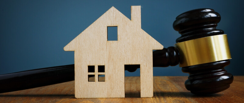 model of wooden home with a gavel behind