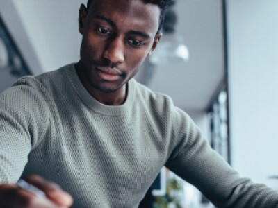 Man by a computer looking down at his notes
