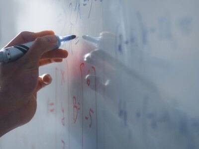 Teacher Writing Equations on a Whiteboard with Mathematical Formulas.