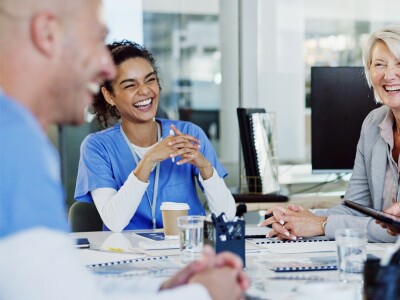 A group of smiling healthcare professionals seated at a table in front of documents.