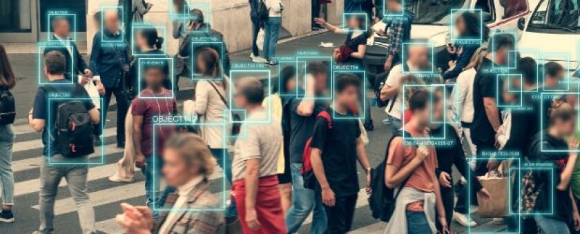 People walking through intersection being digitally face scanned