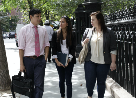 three students talk together while walking on a New York City sidewalk