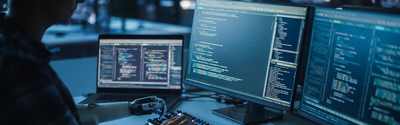 Engineer coding with a prosthetic robot arm.