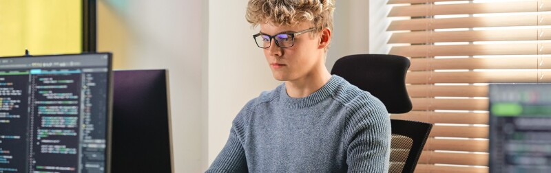 Male intern working on desktop computer in an office space.