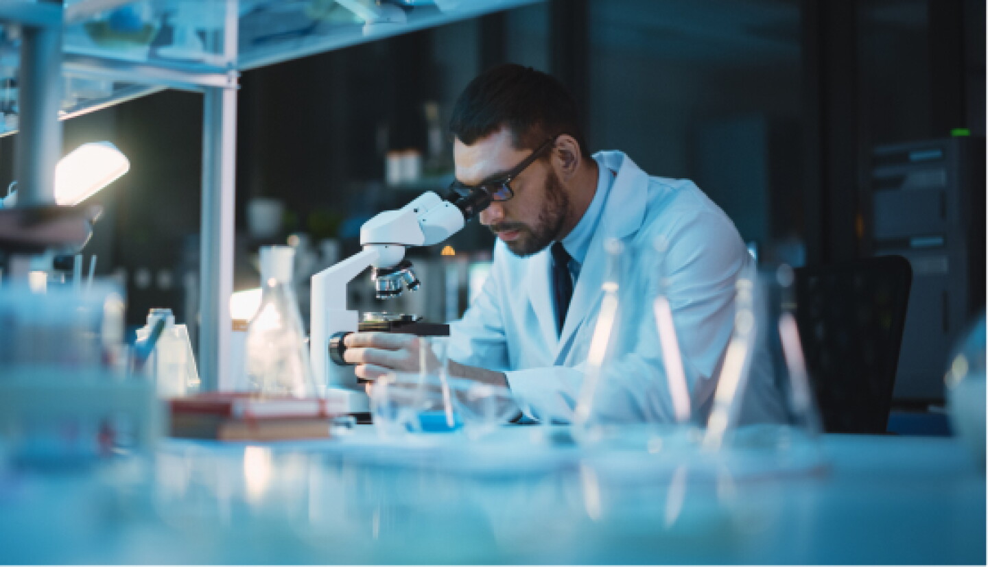 Closeup of a male CWRU student reviewing sample under a microscope.