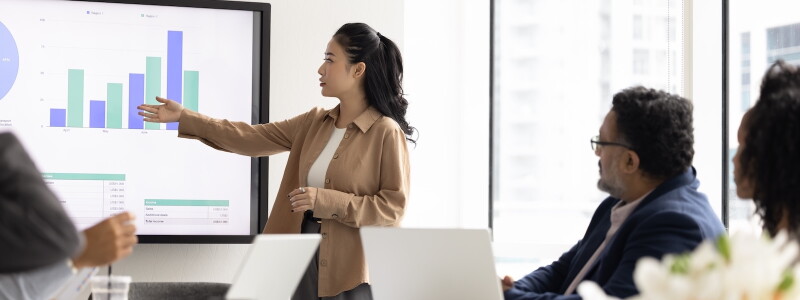 Business analyst presents data visualizations to colleagues during a meeting.