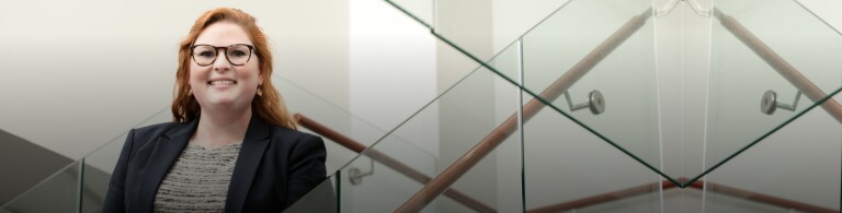 student poses for photo on glass staircase