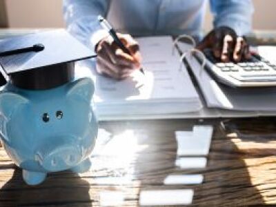 Peron using calculator on a desk next to a piggy bank