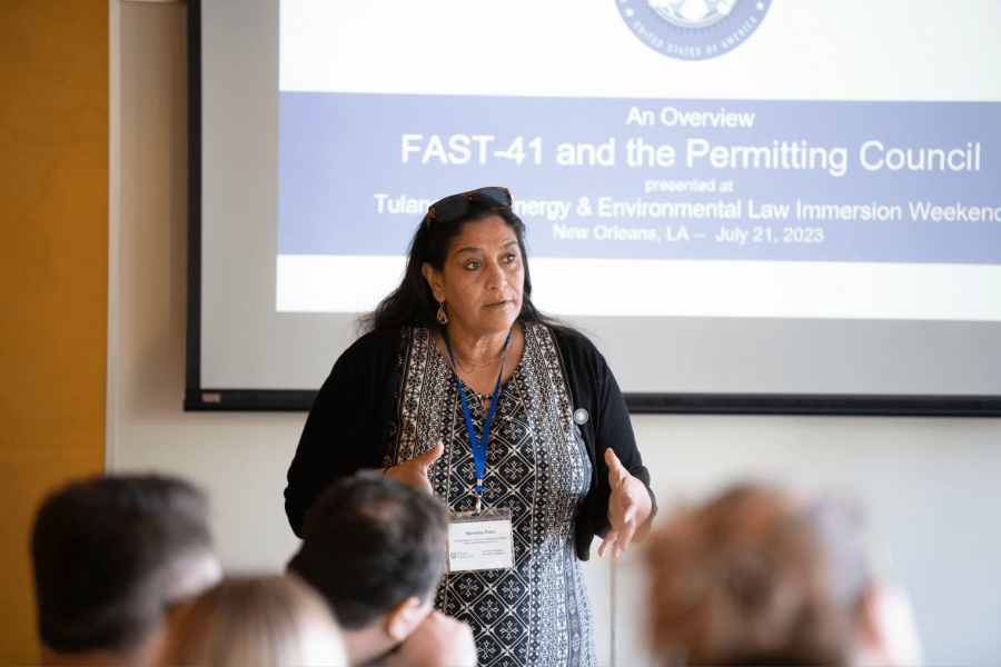 Woman with nametag speaking to room of people in front of projection