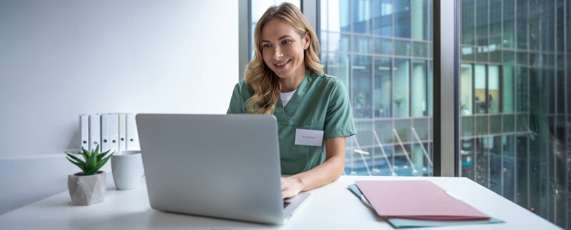 Nurse in scrubs working on her laptop