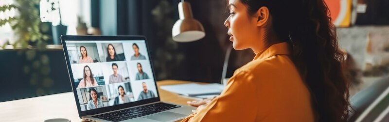 Female social worker sits at a computer while communicating with her team during a video conference call.