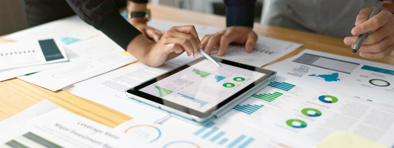 Marketing professionals reviewing digital analytics data on a tablet and printed reports