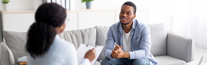 Young black male receiving professional help from female counselor