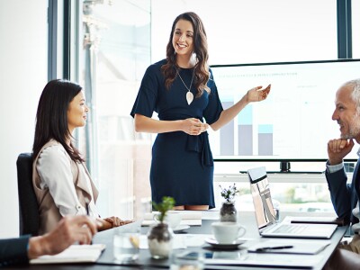 Professional woman presenting data insights on a screen to a group of colleagues