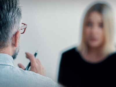 Close-up of a therapist holding a pen talking to his blurred female patient