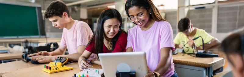 Diverse teenage students building electronic circuits in a high school lab.
