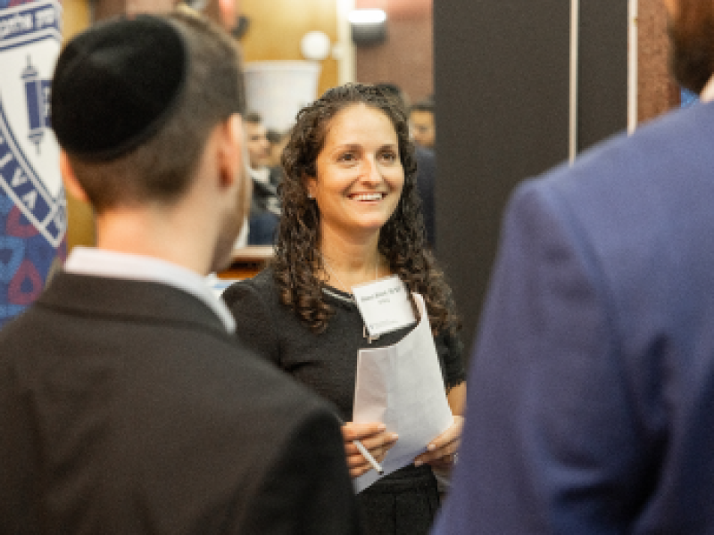 A female Yeshiva University student networks with two male classmates during a networking event on campus.