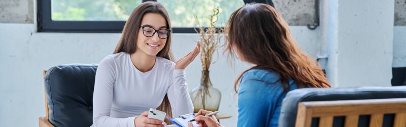 Young smiling girl patient in therapy session with social mental therapist.