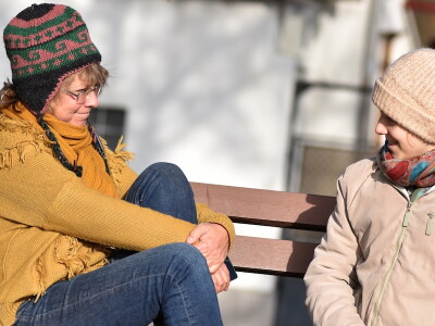 A social worker and her client talk while sitting outdoors in the fall.