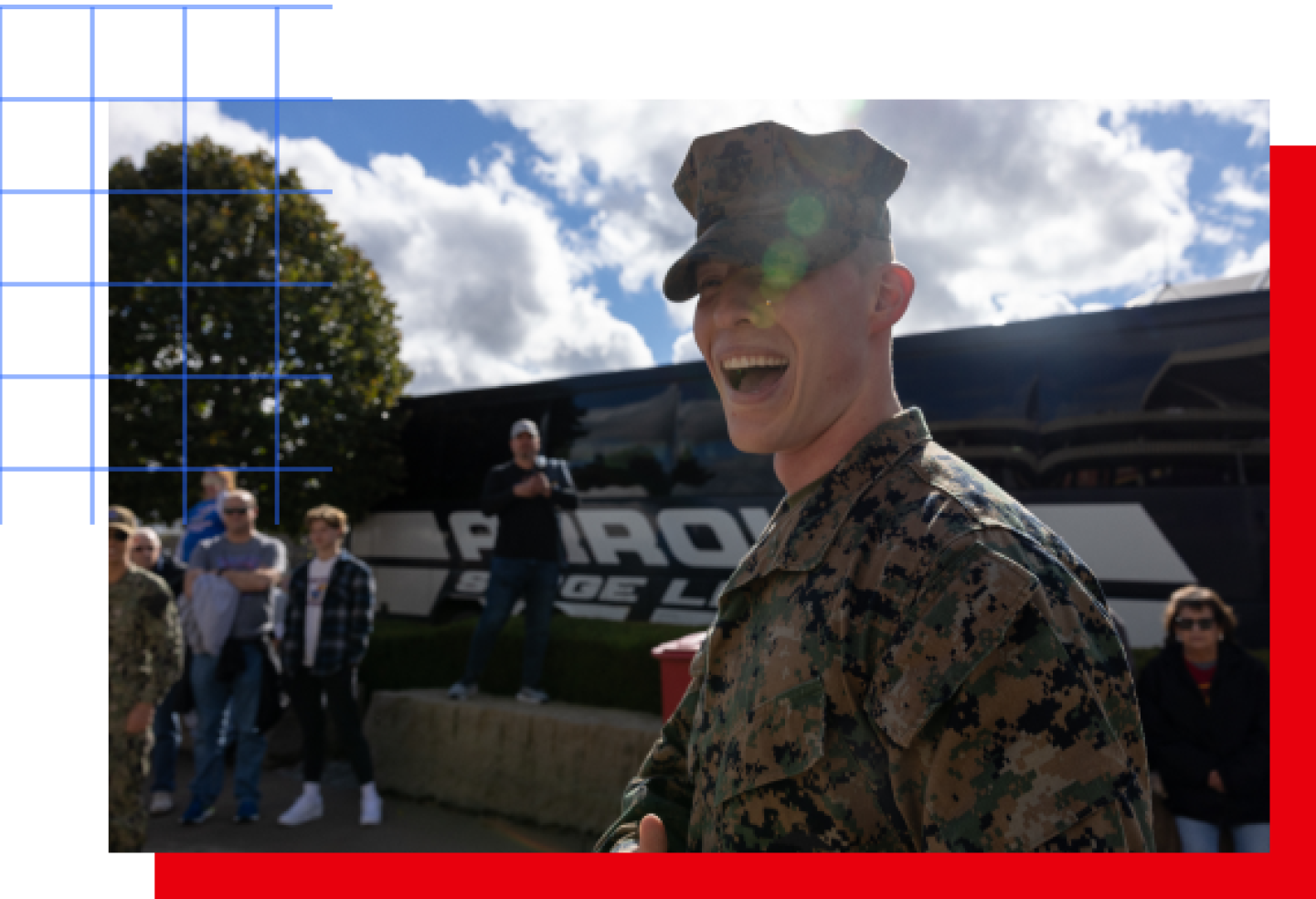 A male service member smiles while standing in front of a bus.