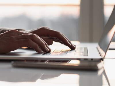 A closeup of the hands of someone working at their desk on a laptop