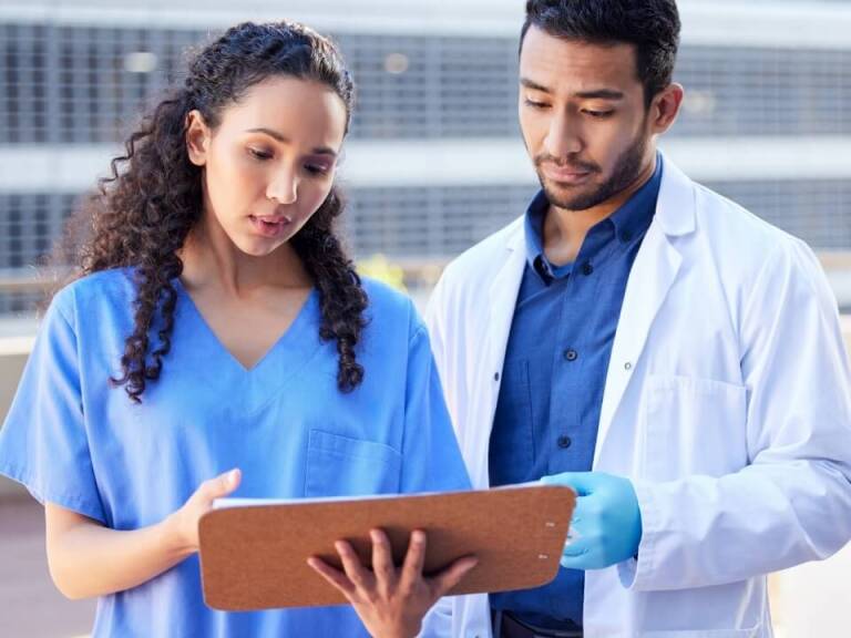 Surgeon and lab technician in uniform looking at clipboard