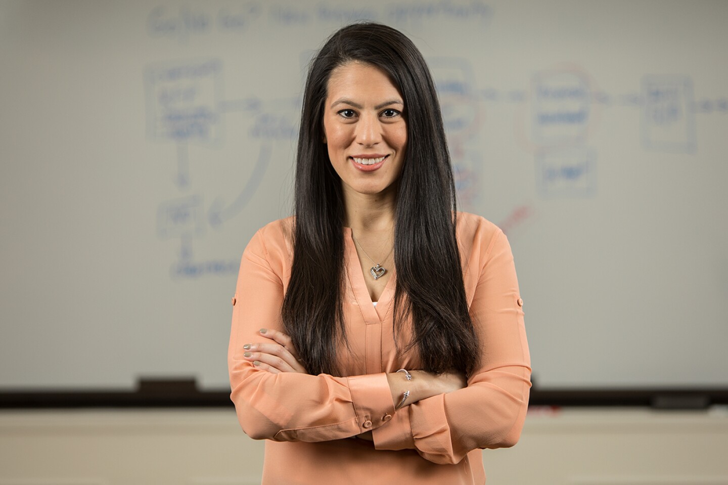 Confident female William & Mary student standing in front of a whiteboard with arms crossed