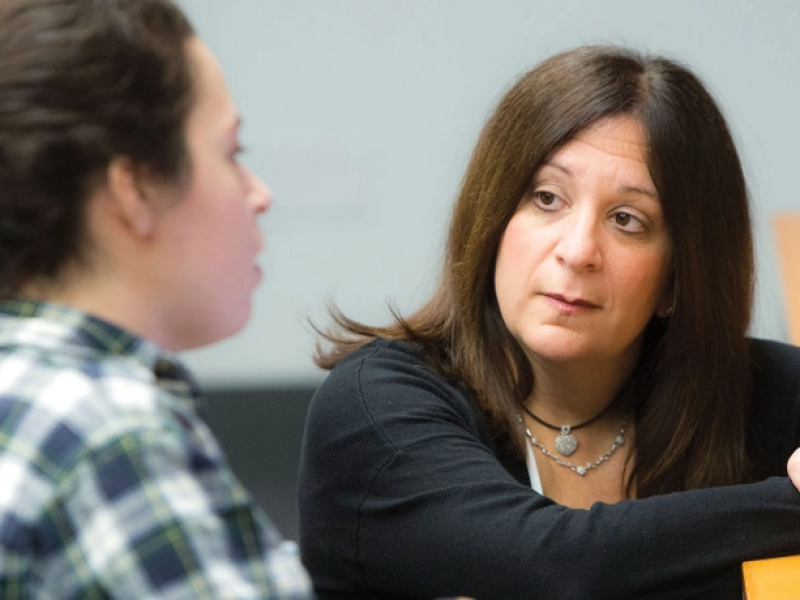 Woman listening intently to student speaking at desk
